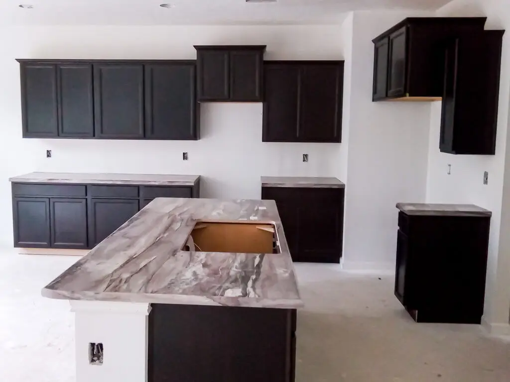 Installed dark shaker kitchen cabinets with island and stone countertop during kitchen renovation